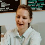 A barista receiving cash from a customer at a coffee shop payment counter, showcasing a transaction.